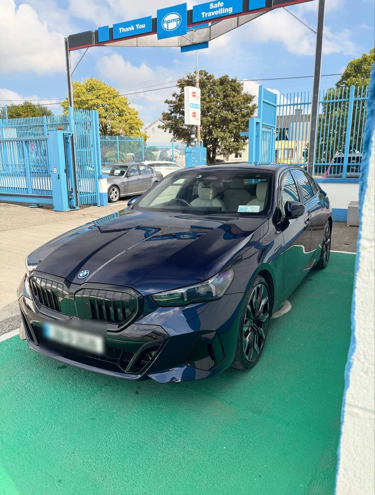 Dark blue BMW 530e from the front, freshly cleaned and parked on a green bay